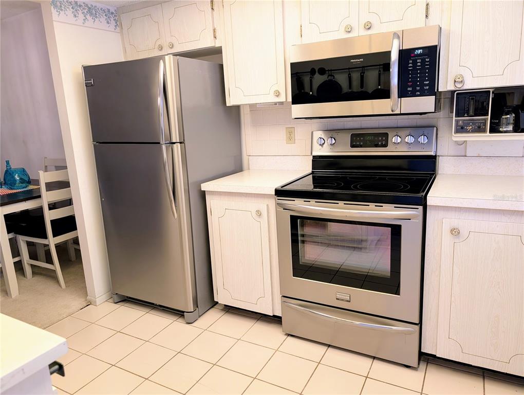A kitchen features white cabinets, stainless steel appliances, and light-colored tile flooring — 3564 LAKE BAYSHORE DRIVE UNIT K-203, BRADENTON, FL