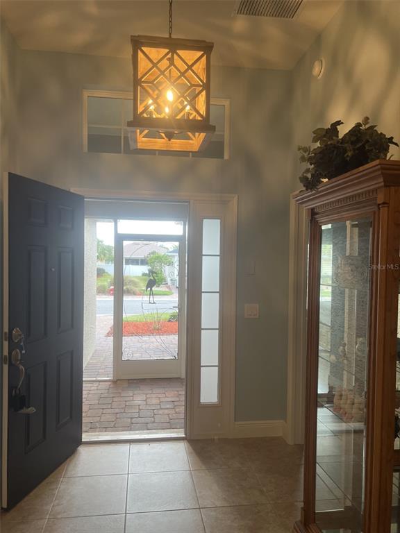 An entryway features a wooden lantern pendant light, tile flooring, and a glass-paneled front door — 4986 BELTED KINGFISHER DRIVE, OXFORD, FL