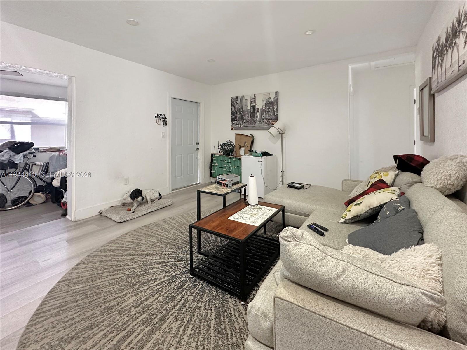 A living room features a sectional sofa, a round area rug, and a dog resting — 971 79th Ter, Miami Beach FL 33141, MIAMI BEACH, FL