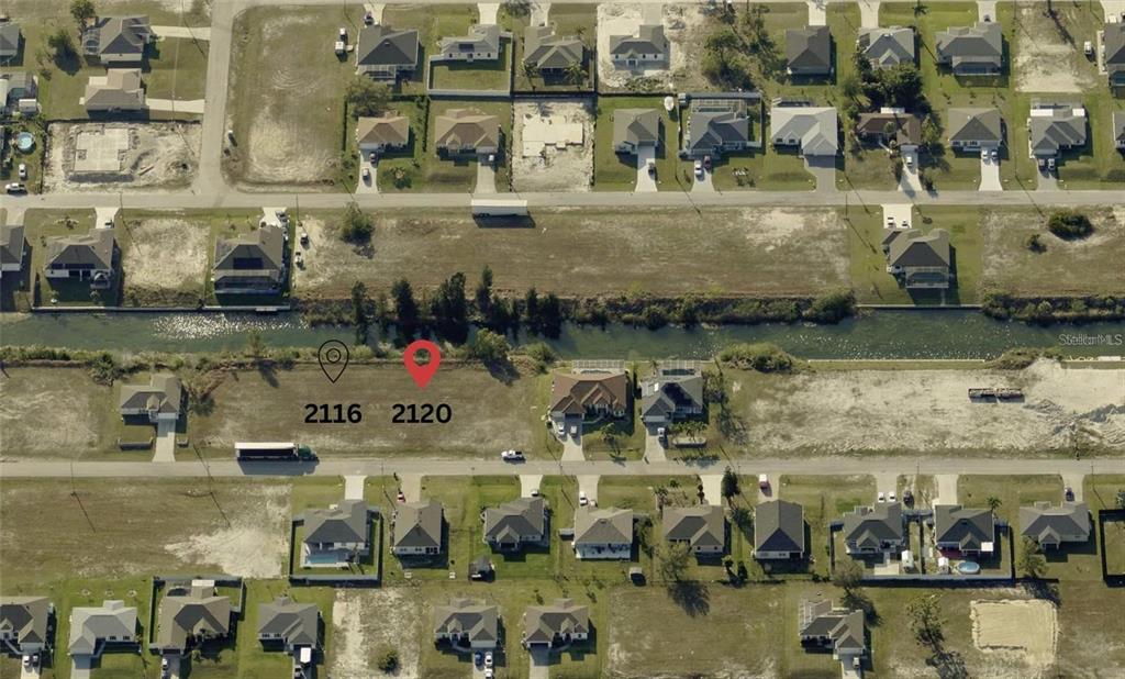 This aerial view shows two vacant residential lots situated along a canal — 2120 NW 17TH AVENUE, CAPE CORAL, FL