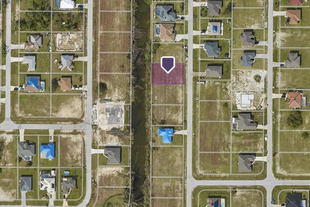 An aerial view shows a vacant residential lot highlighted in purple next to a canal — 2120 NW 17TH AVENUE, CAPE CORAL, FL