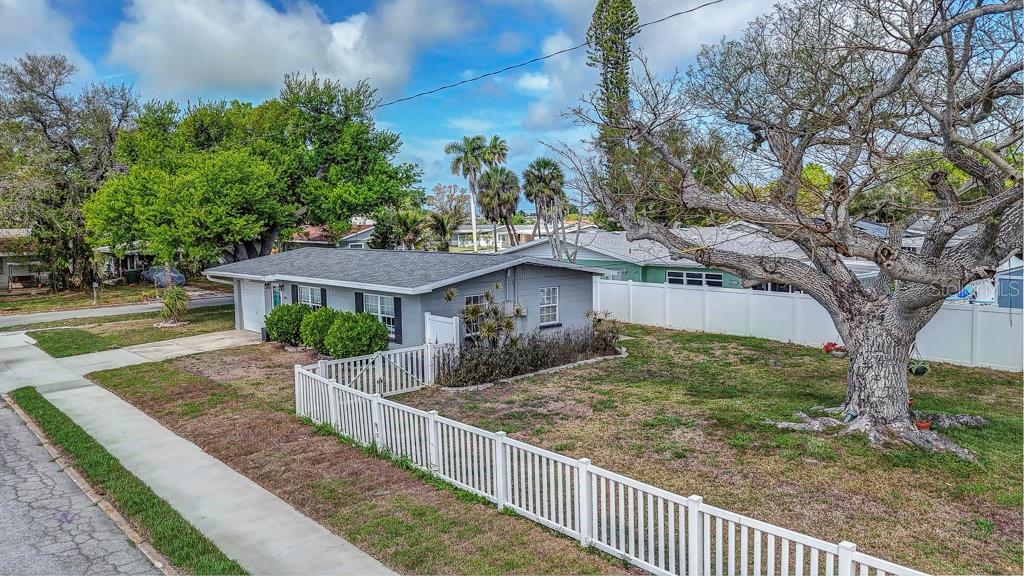 A gray single-story house with a white fence and a large tree in the yard — 1202 26TH AVENUE W, PALMETTO, FL