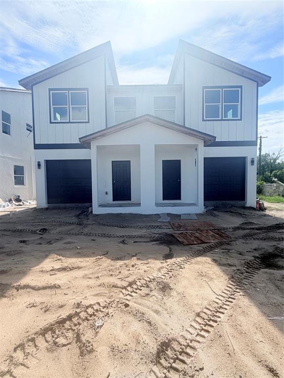 A front view of a newly constructed duplex with white siding, black trim, and garage doors — 3601 N 52ND STREET, TAMPA, FL