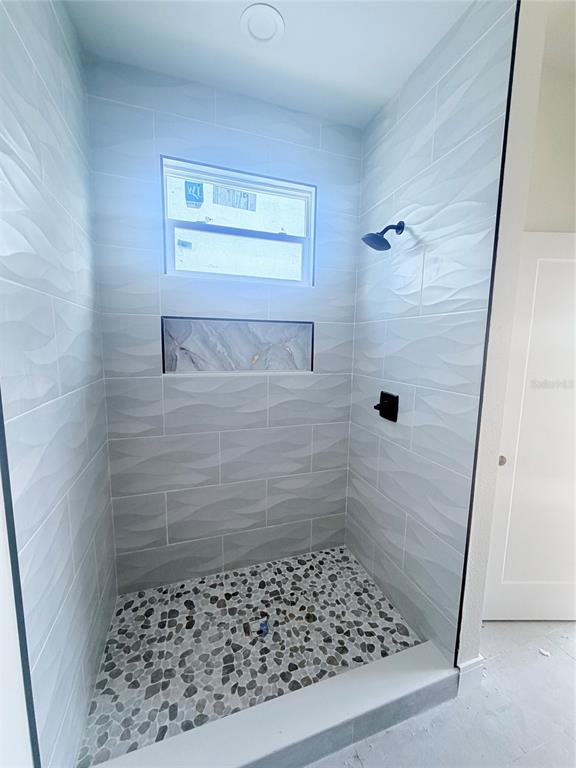 A walk-in shower features textured light gray wall tiles, a pebble floor, and a marble niche — 3601 N 52ND STREET, TAMPA, FL