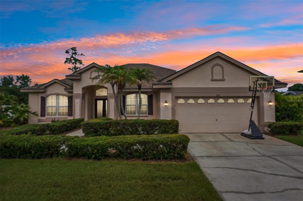 A single-story suburban house with a beige stucco exterior, a two-car garage, and landscaping — 1008 ROBINWOOD DRIVE, OLDSMAR, FL