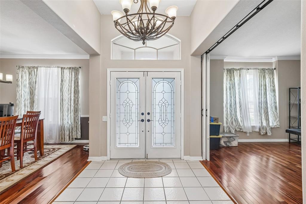 A foyer with a tiled floor, double glass-paneled front doors, and a decorative chandelier — 1008 ROBINWOOD DRIVE, OLDSMAR, FL