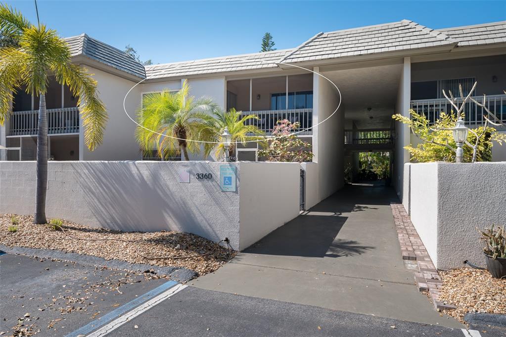 An exterior view of a two-story residential building with a screened balcony and covered walkway — 3360 S OSPREY AVENUE UNIT 205B, SARASOTA, FL