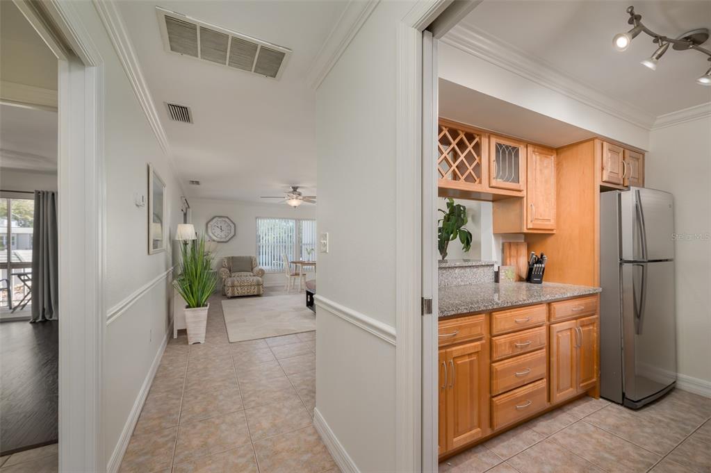 A kitchen with wood cabinets and granite countertops opens into a tiled living area — 3360 S OSPREY AVENUE UNIT 205B, SARASOTA, FL