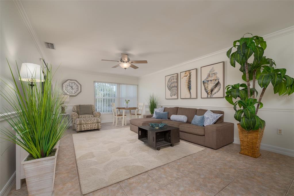 A living room features a brown sectional sofa, a patterned armchair, and a large plant — 3360 S OSPREY AVENUE UNIT 205B, SARASOTA, FL