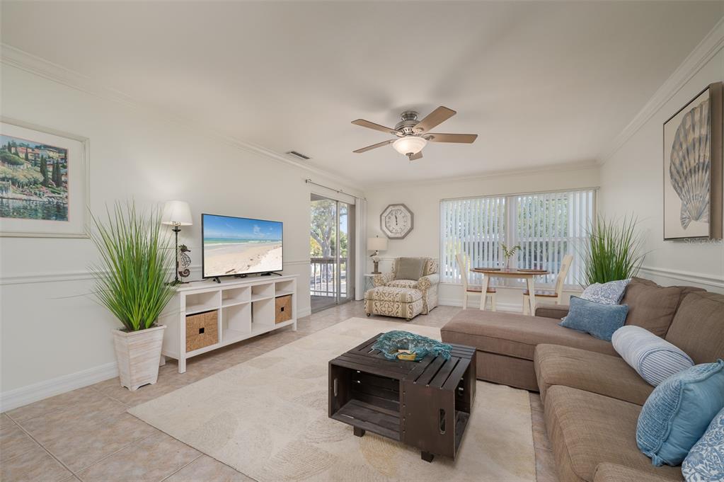 A living room features a sectional sofa, a television on a console, and a ceiling fan — 3360 S OSPREY AVENUE UNIT 205B, SARASOTA, FL