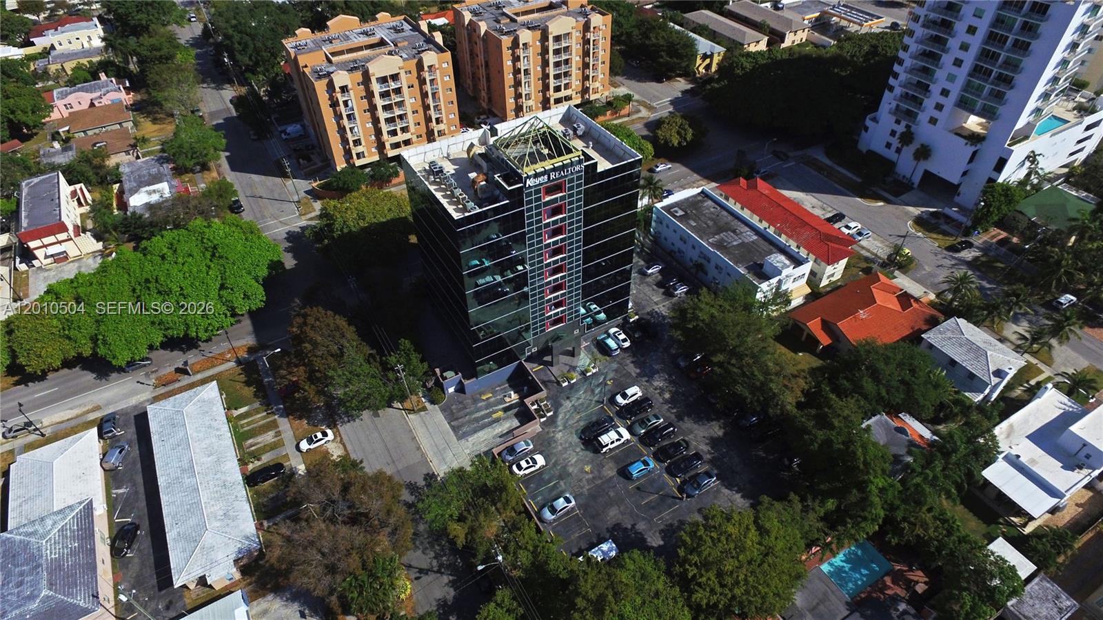 An aerial view shows a dark glass office building surrounded by parking and residential structures — 2121 SW 3rd Ave # 200, Miami FL 33129, MIAMI, FL