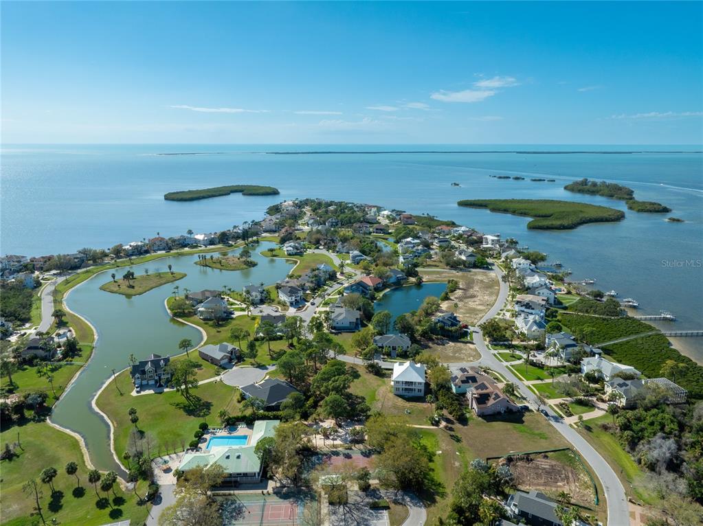 An aerial view shows a coastal residential community with houses, ponds, and surrounding water — HARBOUR WATCH DRIVE, TARPON SPRINGS, FL