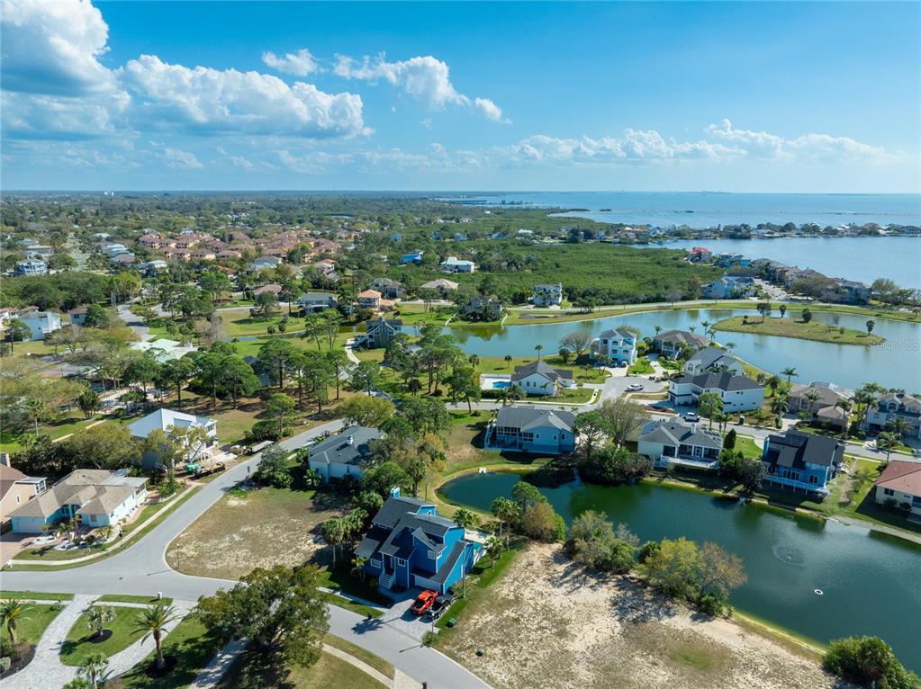 An aerial view shows suburban houses situated around small ponds near a large bay — HARBOUR WATCH DRIVE, TARPON SPRINGS, FL