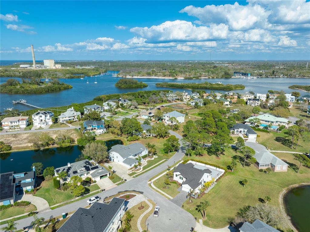 An aerial view shows a suburban neighborhood with houses, ponds, and a nearby power plant — HARBOUR WATCH DRIVE, TARPON SPRINGS, FL