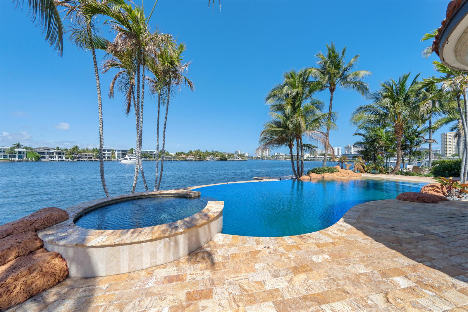 A waterfront infinity pool and hot tub feature stone decking and palm trees — 2593 SE 8th Street, Pompano Beach FL 33062, POMPANO BEACH, FL