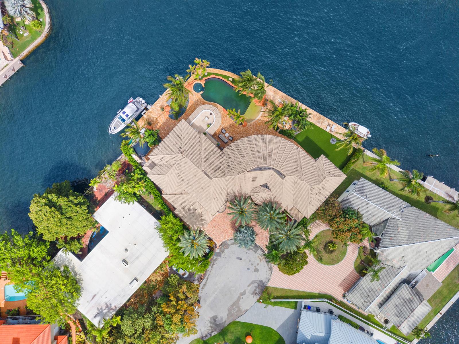 An aerial view shows a waterfront house with a curved roof, pool, and boat dock — 2593 SE 8th Street, Pompano Beach FL 33062, POMPANO BEACH, FL
