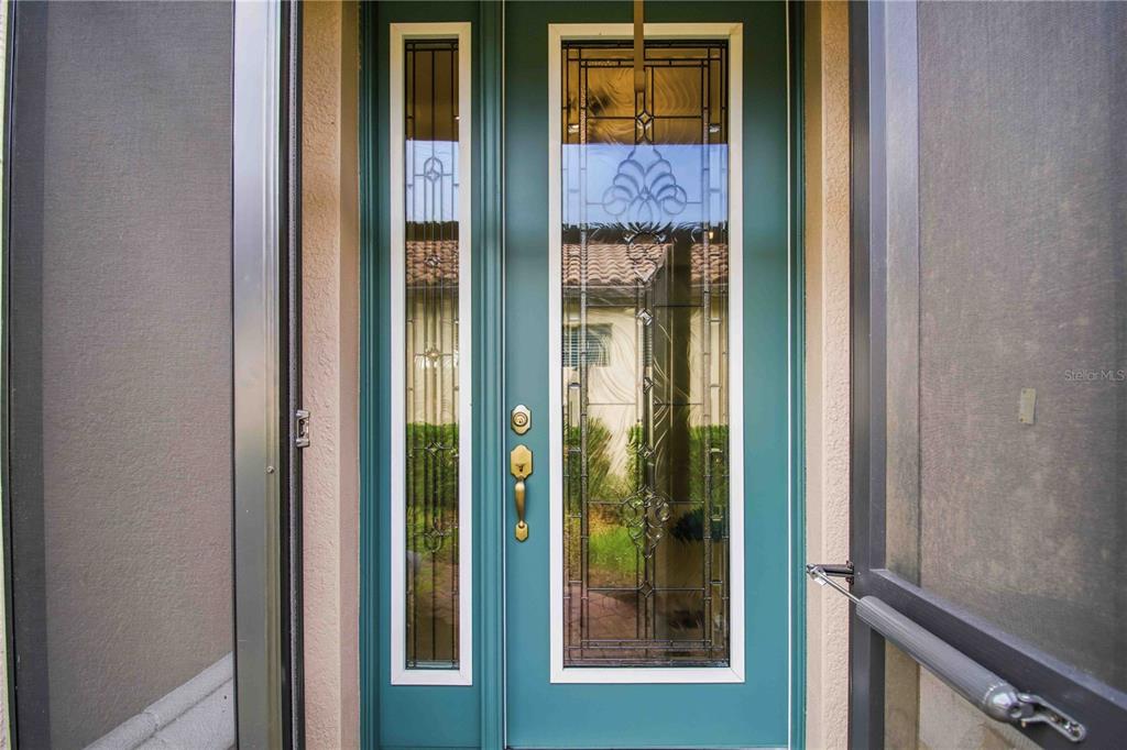 A dark metal screen door is installed over the front entrance of a stucco home — 10437 HIGHLAND PARK PLACE, PALMETTO, FL
