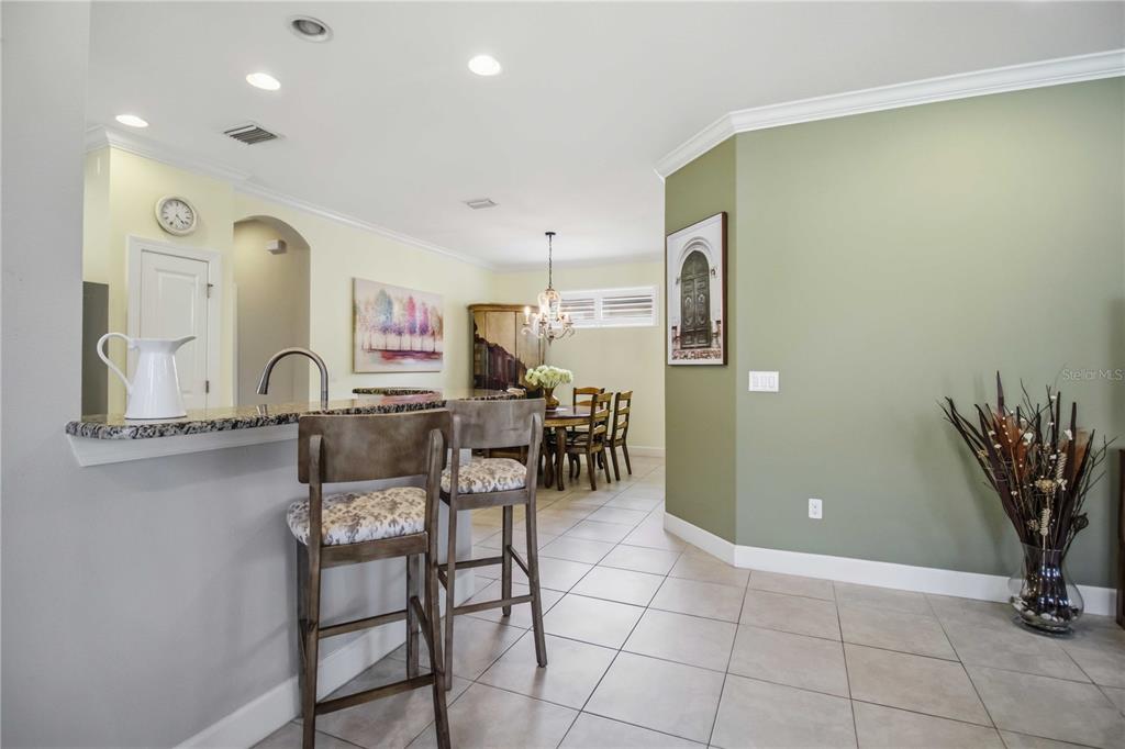 A living room features tile floors, a gray sofa, two armchairs, and a glass-paneled door — 10437 HIGHLAND PARK PLACE, PALMETTO, FL