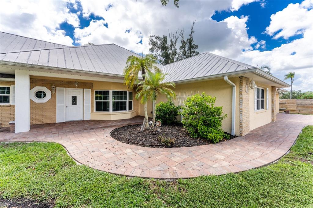 A single-story house with a metal roof, brick accents, and a curved paver walkway — 200 S OXFORD DRIVE, ENGLEWOOD, FL