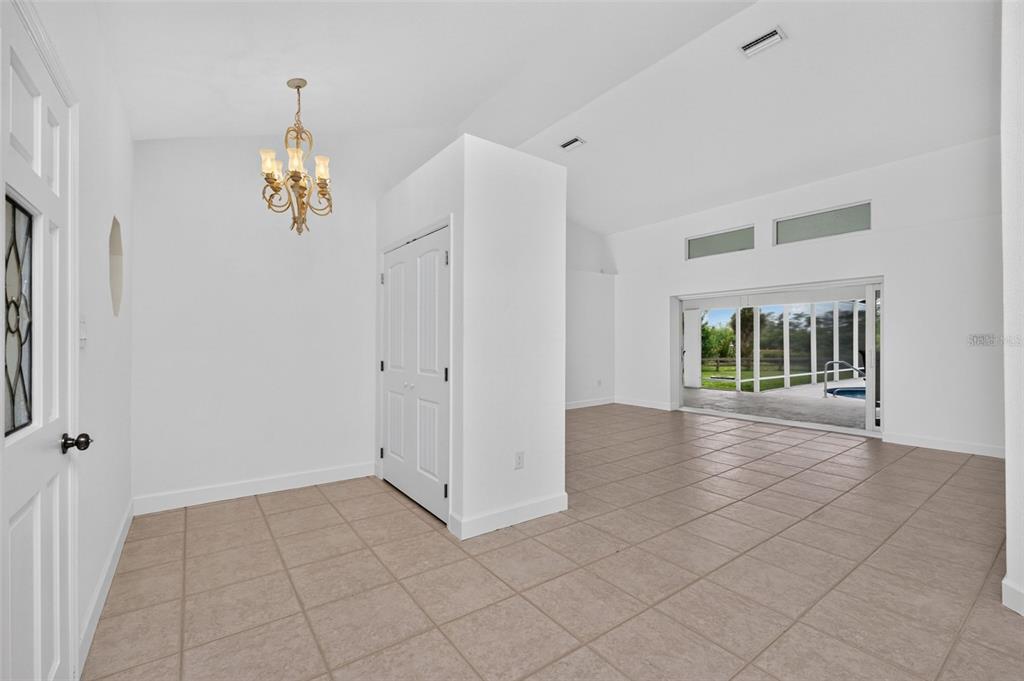 An entryway with a chandelier leads into a tiled living area with sliding glass doors — 200 S OXFORD DRIVE, ENGLEWOOD, FL