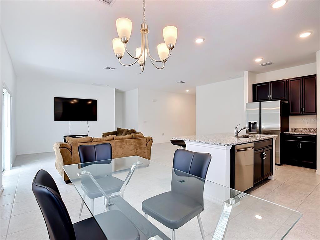 An open-concept living area features a dining table, kitchen island, and a mounted television — 1414 ORLANDO COURT, POINCIANA, FL