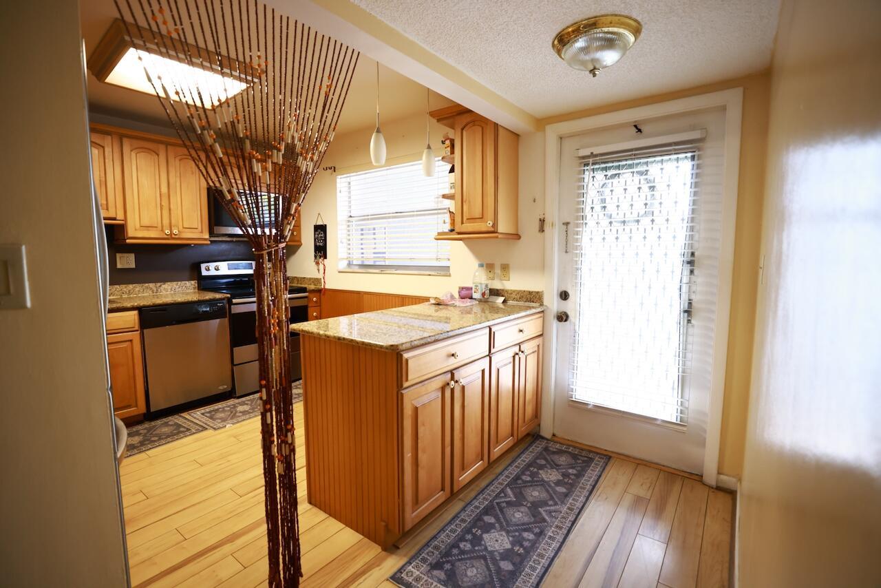 A kitchen with wood cabinets, granite countertops, stainless steel appliances, and a bead curtain divider — 6570 Royal Palm Boulevard # 106j, Margate FL 33063, MARGATE, FL