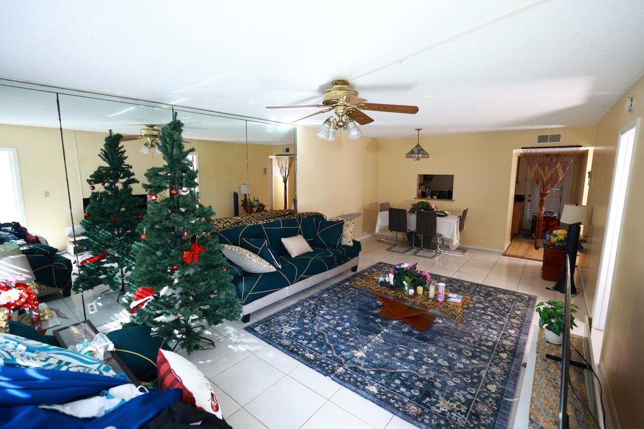 A living room with a mirrored wall, a Christmas tree, a sofa, and a dining area — 6570 Royal Palm Boulevard # 106j, Margate FL 33063, MARGATE, FL