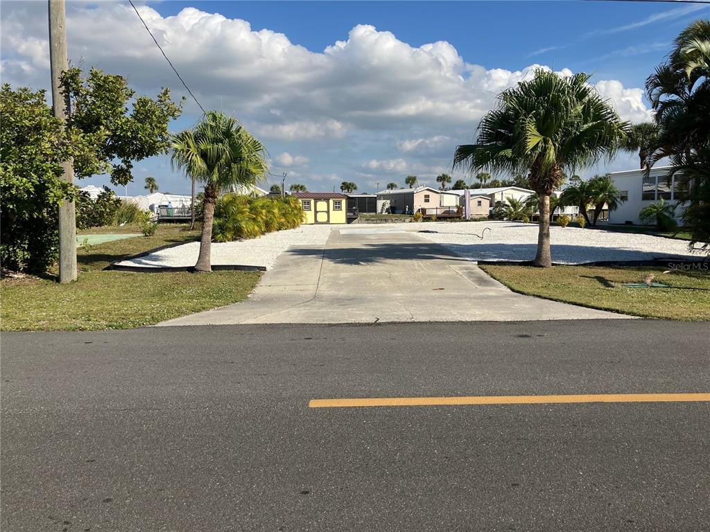A paved driveway leads to a yellow shed on a lot with white gravel — 1447 FLAMINGO DRIVE, ENGLEWOOD, FL