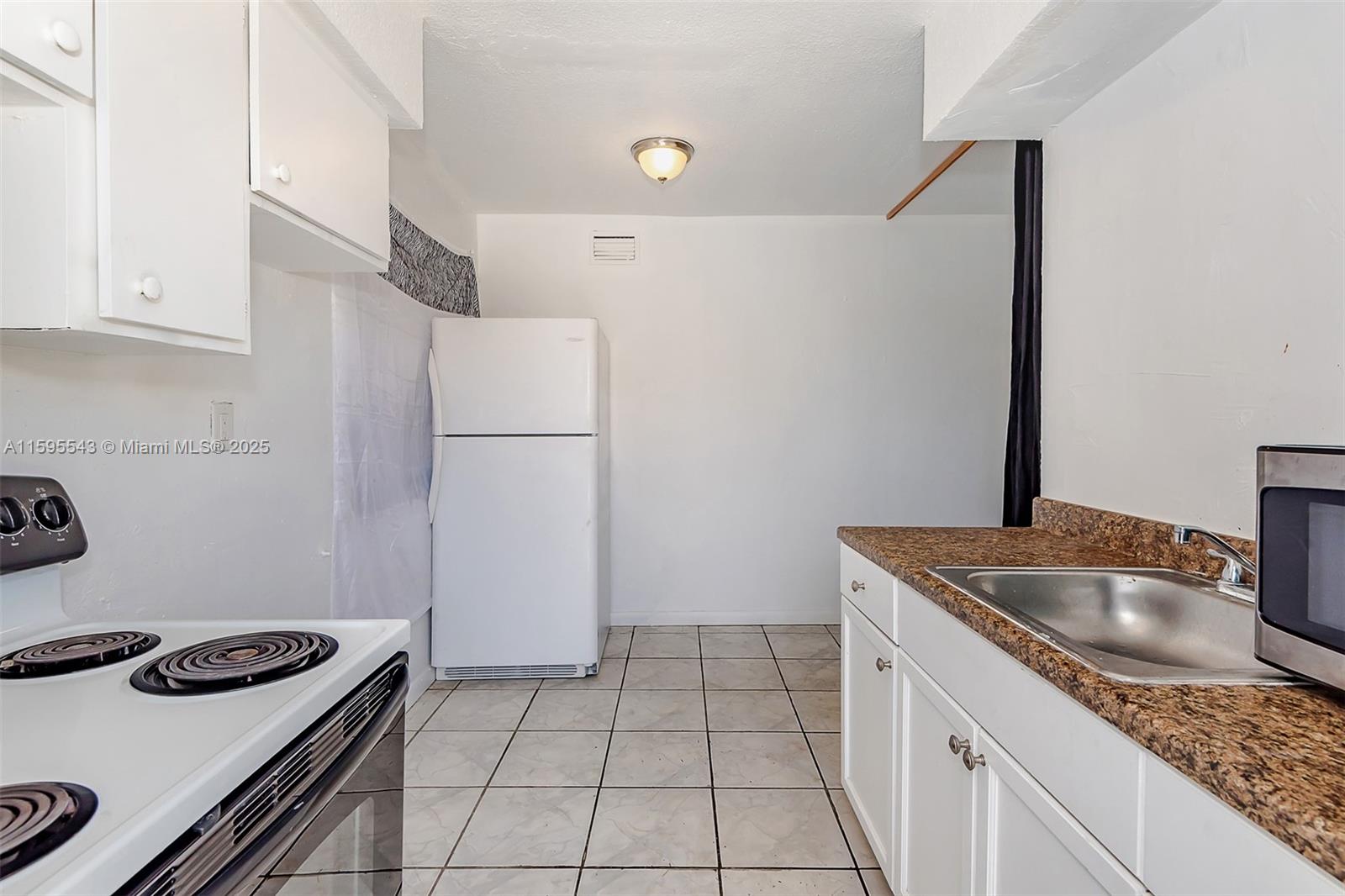 A kitchen features white cabinets, a white stove, a refrigerator, and a stainless steel sink — 5600 NW 7th Ct # 14, Miami FL 33127, MIAMI, FL