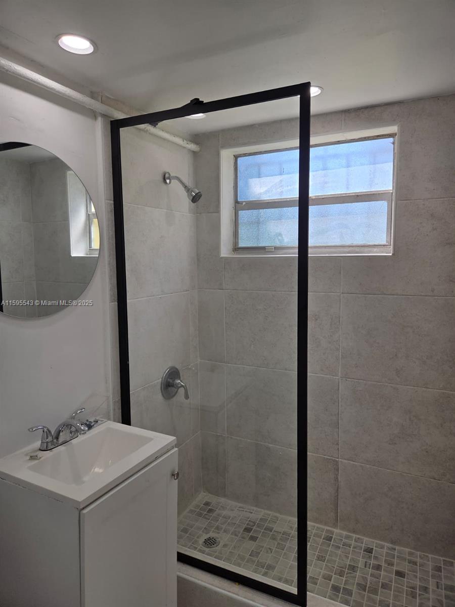 A bathroom features a walk-in shower with a black frame, light tiles, and a vanity — 5600 NW 7th Ct # 14, Miami FL 33127, MIAMI, FL