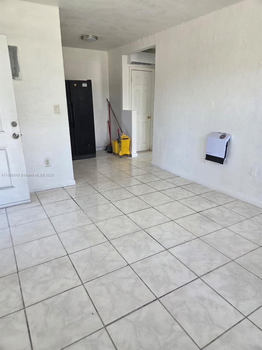 A room with white walls, light-colored tile flooring, a black refrigerator, and a cleaning bucket — 5600 NW 7th Ct # 14, Miami FL 33127, MIAMI, FL