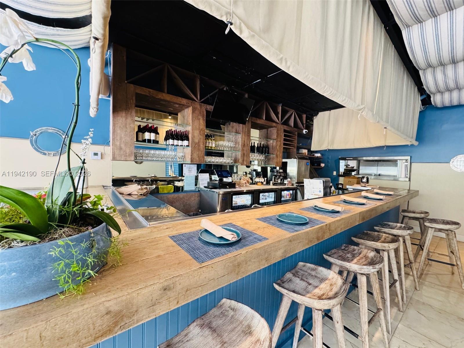 A bar area features a wooden counter, blue paneling, and several stools under a canopy — 1965 NE 2nd St, Deerfield Beach FL 33441, DEERFIELD BEACH, FL