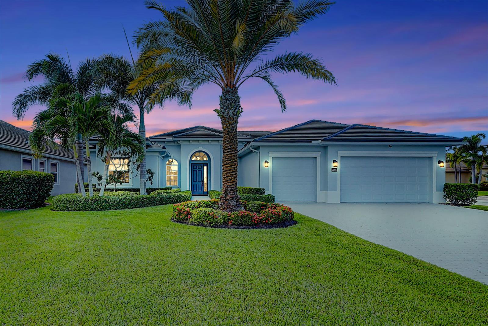 A single-story house with a blue exterior, a palm tree, and a two-car garage — 7186 SW Quiet River Court, Stuart FL 34997, STUART, FL