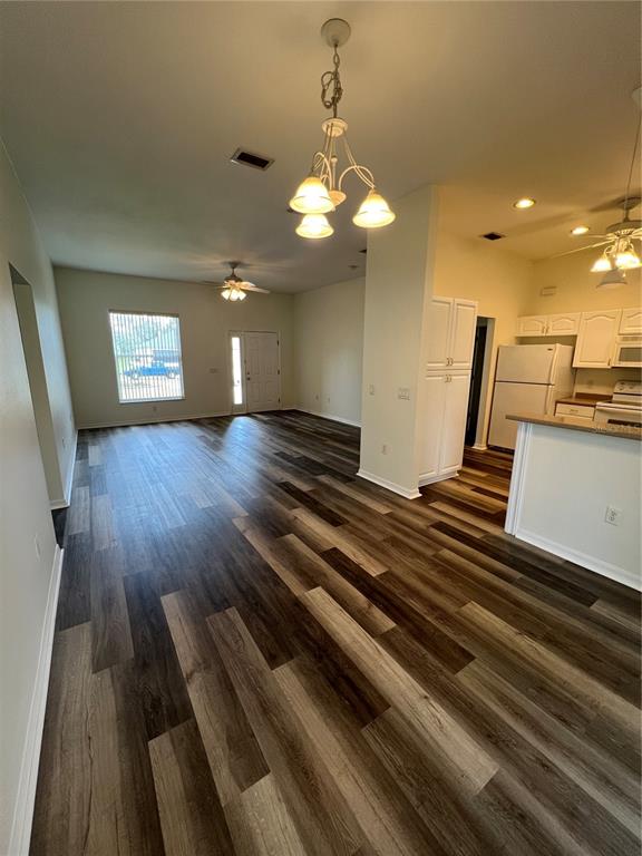 An open-concept kitchen and living area features wood-look flooring and two hanging light fixtures — 4733 S CRANBERRY BOULEVARD, NORTH PORT, FL