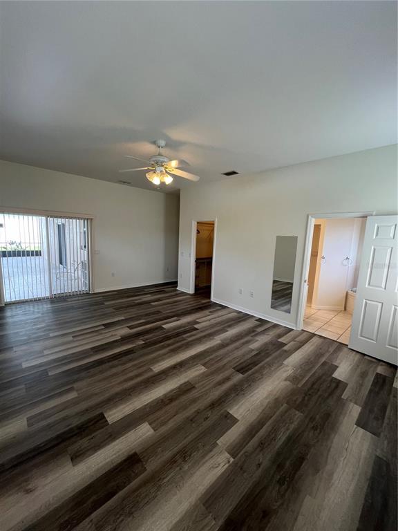 A spacious bedroom features wood-look flooring, a ceiling fan, a walk-in closet, and sliding doors — 4733 S CRANBERRY BOULEVARD, NORTH PORT, FL
