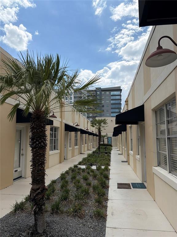 An outdoor walkway between two rows of beige buildings features a palm tree and landscaping — 320 N MAGNOLIA AVENUE UNIT Suite B4, ORLANDO, FL