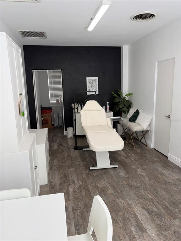 A treatment room features a white aesthetic bed, wood-look flooring, and a black accent wall — 320 N MAGNOLIA AVENUE UNIT Suite B4, ORLANDO, FL