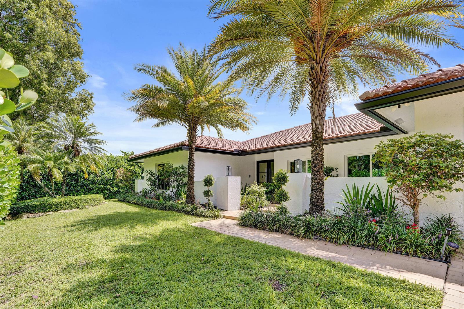 A white house with a tile roof and palm trees sits behind a front lawn — 2804 Banyan Boulevard Circle NW, Boca Raton FL 33431, BOCA RATON, FL