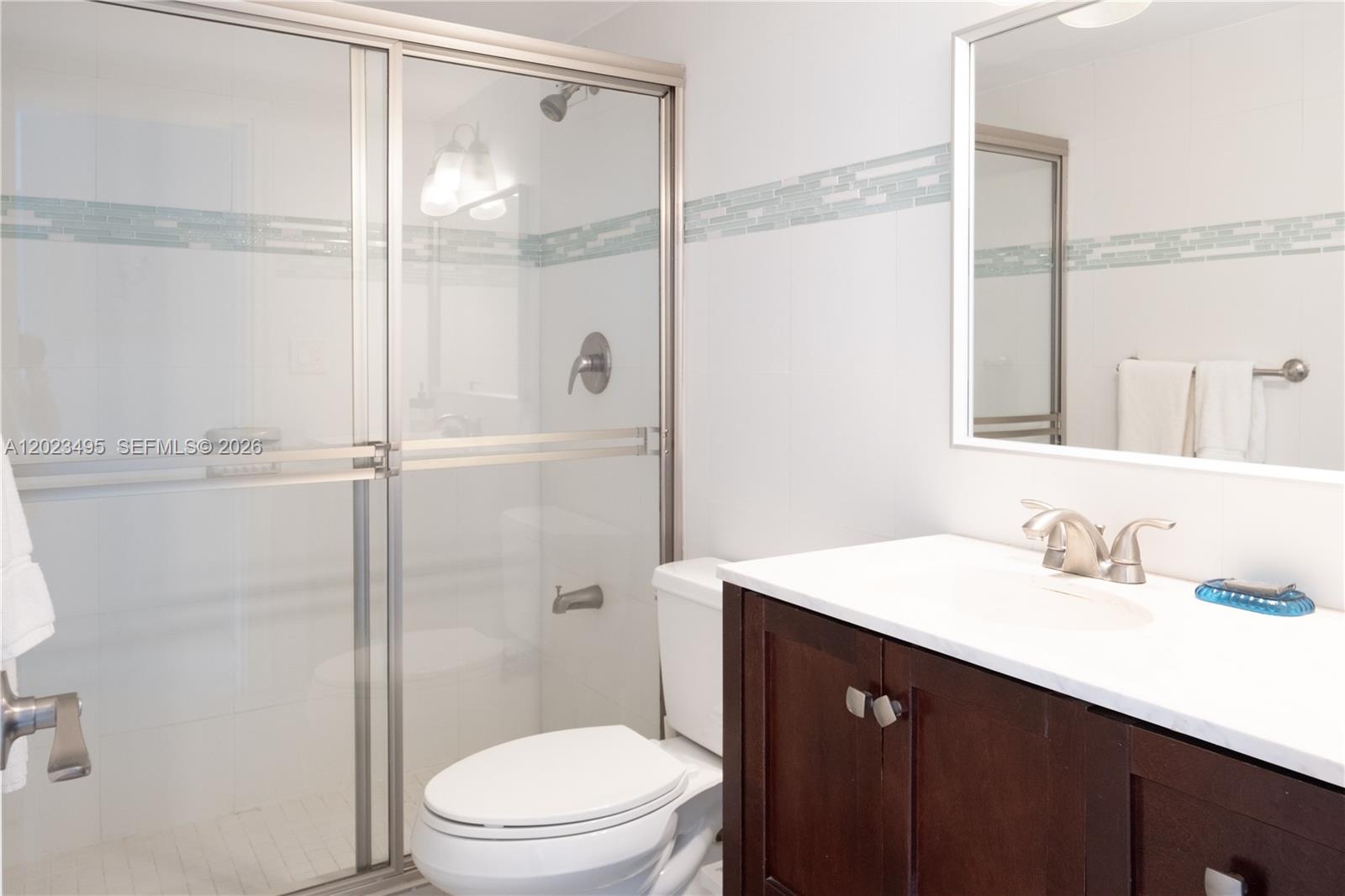 A bathroom features a glass-enclosed shower, a white toilet, and a dark wood vanity — 5601 Collins Ave # 1420, Miami Beach FL 33140, MIAMI BEACH, FL