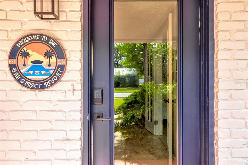 A white brick exterior wall features a round resort sign next to a dark blue door — 2365 BAY STREET, SARASOTA, FL