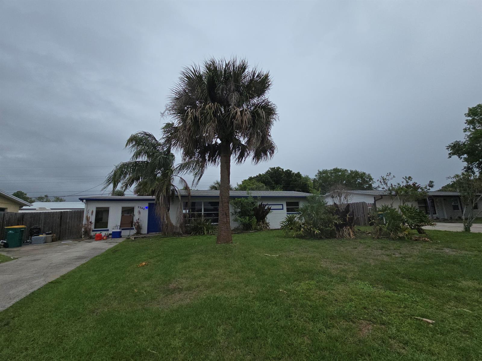 A single-story house with a large palm tree in the front yard under a cloudy sky — 2342 Leewood Boulevard, Melbourne FL 32935, MELBOURNE, FL