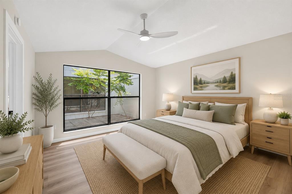 A bedroom with a bed, large window, ceiling fan, and light wood flooring — 647 BONNIE BOULEVARD, PALM HARBOR, FL