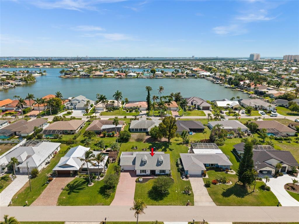 An aerial view shows a single-story house with a red arrow pointing to its roof — 706 SW 51ST TERRACE, CAPE CORAL, FL