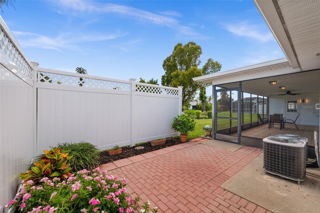 A brick patio sits beside a screened-in porch and a white vinyl privacy fence — 706 SW 51ST TERRACE, CAPE CORAL, FL