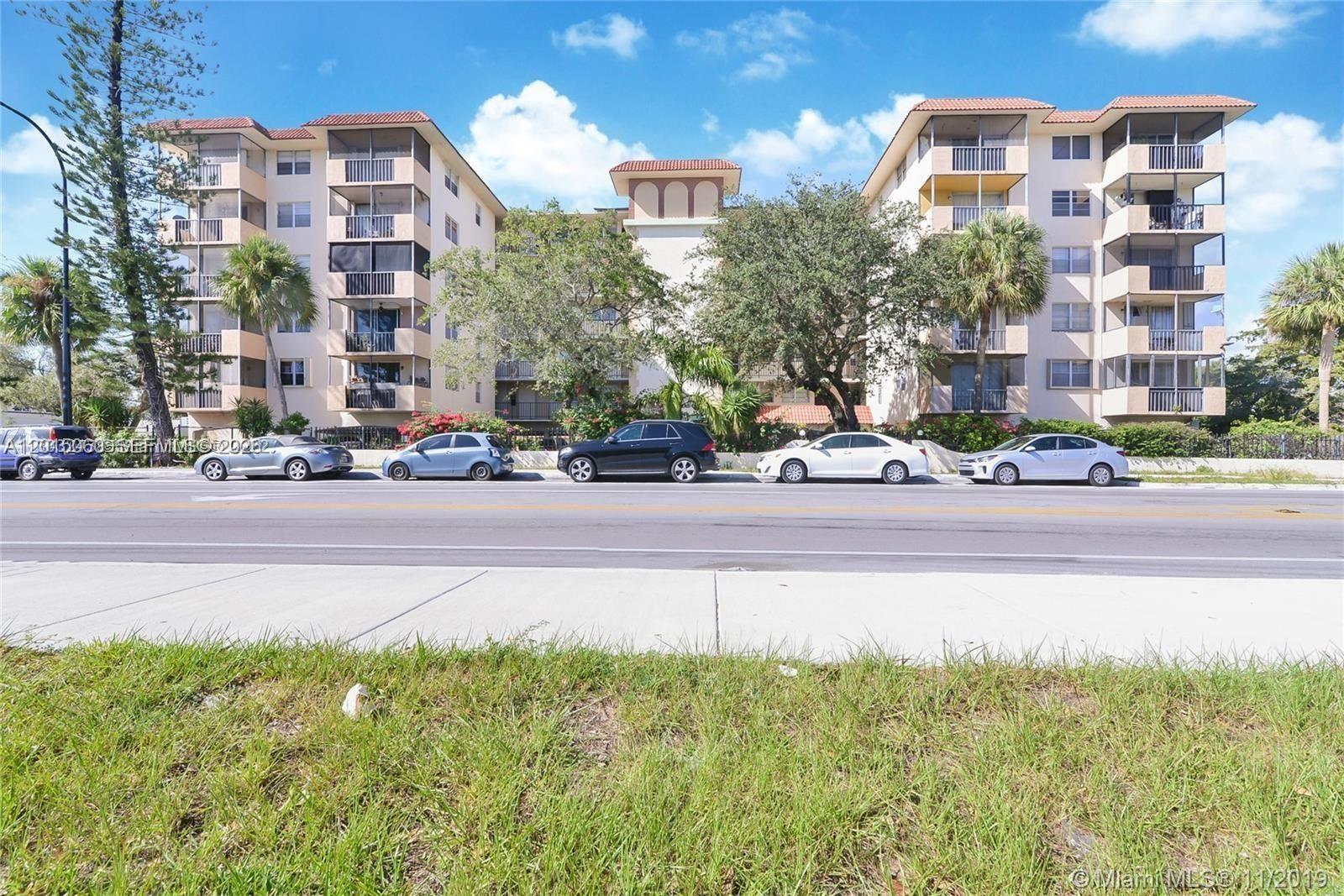 A multi-story residential apartment building with balconies sits behind a street with parked cars — 12590 NE 16th Ave # 210, North Miami FL 33161, NORTH MIAMI, FL