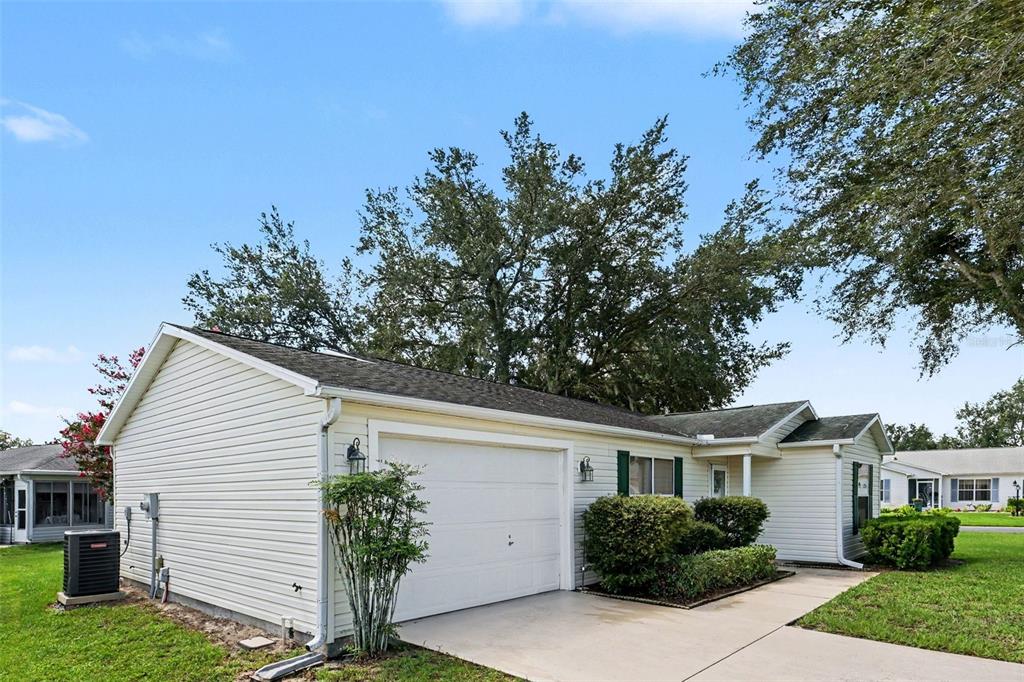 A single-story house with beige siding, a white garage door, and a concrete driveway — 1501 LAS PACOS COURT, THE VILLAGES, FL
