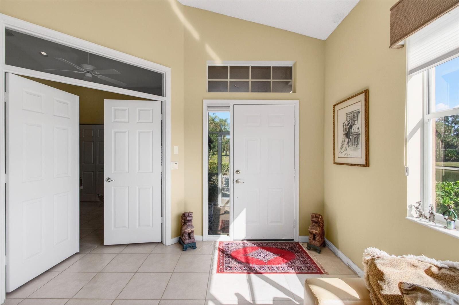 An entryway features a white front door, tile flooring, a red rug, and yellow walls — 6862 Swansea Lane, Boynton Beach FL 33472, BOYNTON BEACH, FL