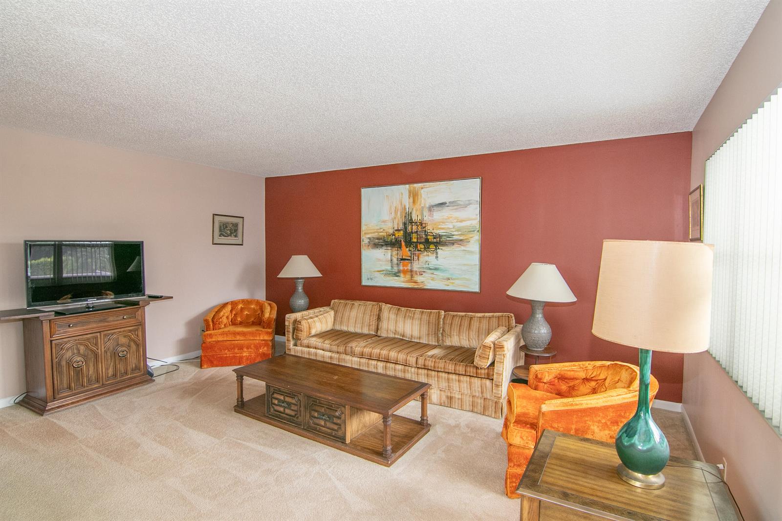 A living room features a striped sofa, two orange velvet chairs, and a red accent wall — 39 Burgundy A, Delray Beach FL 33484, DELRAY BEACH, FL