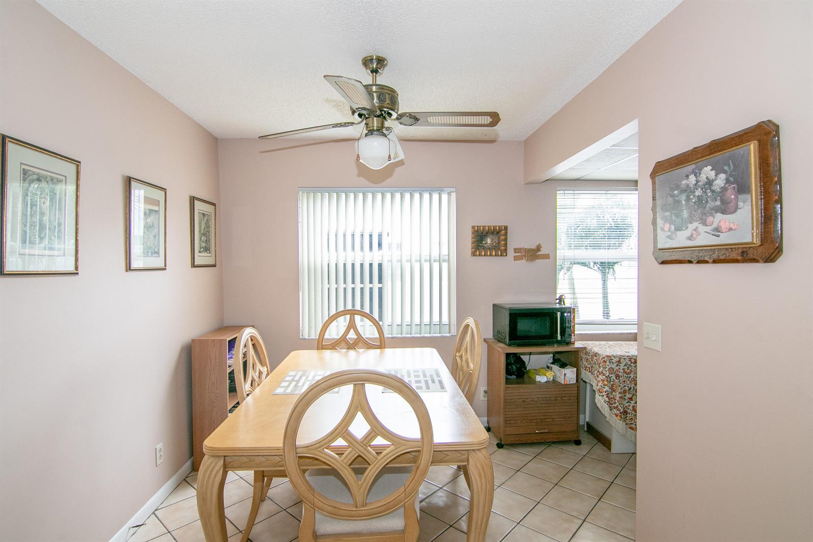 A dining room features a wooden table, four chairs, a ceiling fan, and tiled floors — 39 Burgundy A, Delray Beach FL 33484, DELRAY BEACH, FL