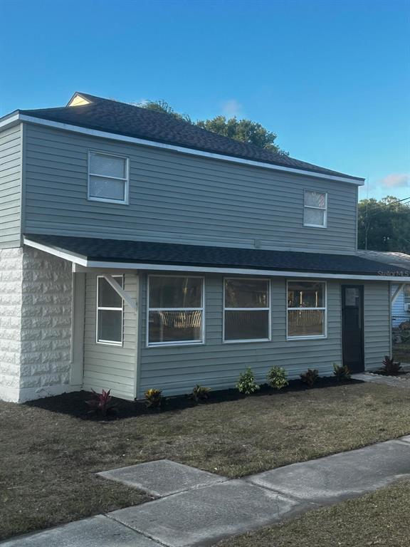 A two-story house with light green siding, a white stone corner, and a dark roof — 716 TROPIC STREET, TITUSVILLE, FL